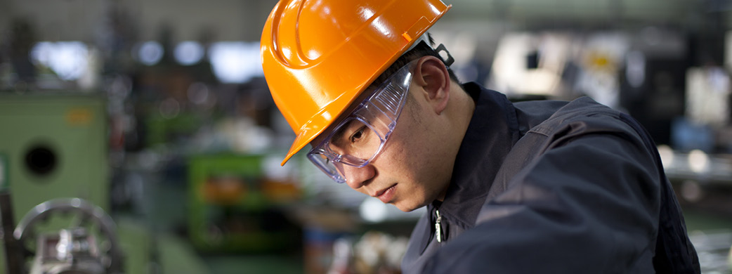 Man wearing safety glasses and hat in industrial area