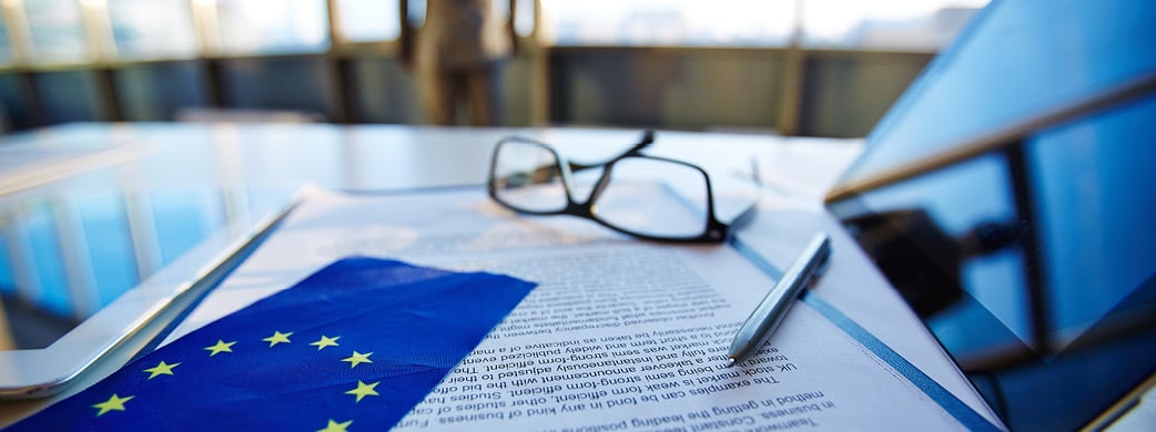 European Union flag and contract on desk with glasses and tablet